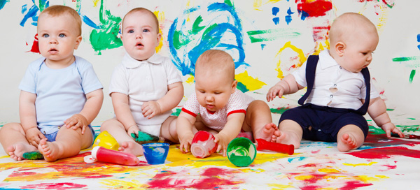 Four barefoot babies playing with paints